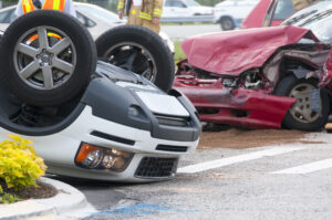 A red car with smashed front end and white car flipped upside down according to an uber accident lawyer Columbus OH